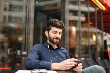 Öğrenci smartphone ve kafede kulaklık ile müzik dinlemek