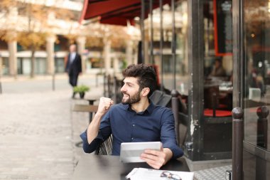 Hoşnutsuz adam online oyun tarafından tablet sokak café'de oynuyor..