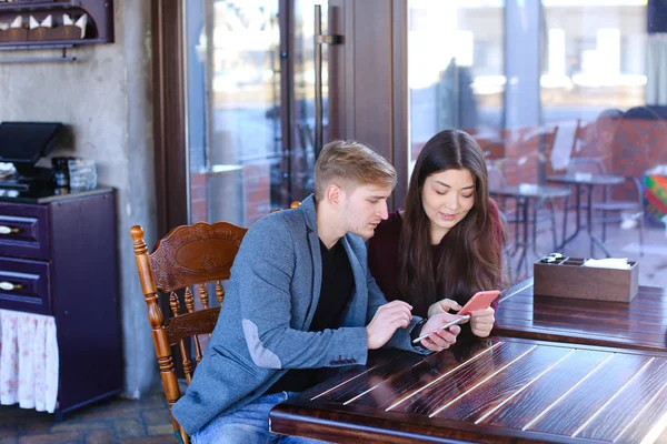 Future parents choosing clothes for child in coffee house with s