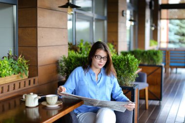 Restoranda gazete okuma ve çay içme büyüleyici kadın