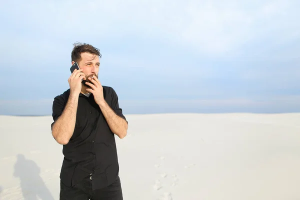 Amateur photographer guy speaking on smartphone at seaside.