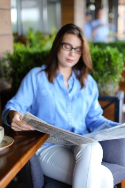 Restoranda gazete okuma ve çay içme büyüleyici kadın