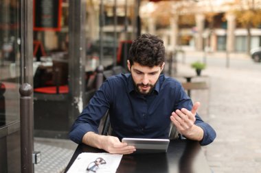 Hoşnutsuz adam online oyun tarafından tablet sokak café'de oynuyor..