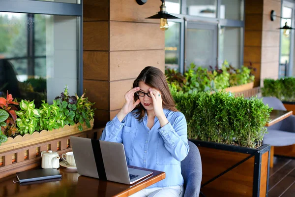 Freelancer hablando por smartphone y trabajando con laptop en cafetería — Foto de Stock