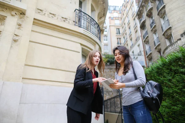 Beautiful girl talking with foreign Chinese student keeping tabl