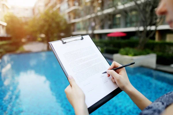 Retrato de cerca de la chica que firma documentos sobre el fondo de la piscina de día soleado. Frente utilizado con licencia Open Font — Foto de Stock