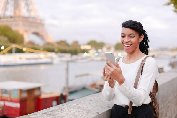 Young woman standing on embankment in Paris and watching photos 