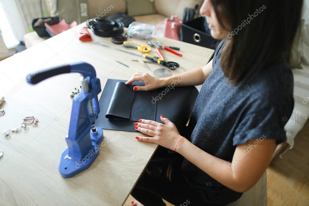 girl preparing leather for making purse.