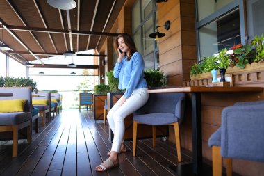 Genç kız yanında smartphone restoranda konuşuyor  .