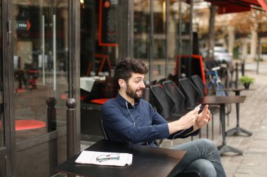 Öğrenci smartphone ve kafede kulaklık ile müzik dinlemek