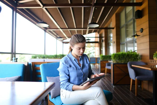 Chica bonita trabajando con la tableta en la cafetería . — Foto de Stock