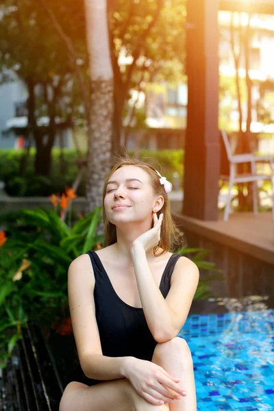 Mujer joven disfrutar, relajarse cerca de palmeras y edificio de apartamentos en el país tropical con la luz del sol — Foto de Stock