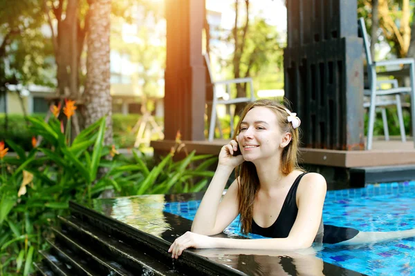 Hermosa mujer haciendo llamada nadando en la piscina — Foto de Stock