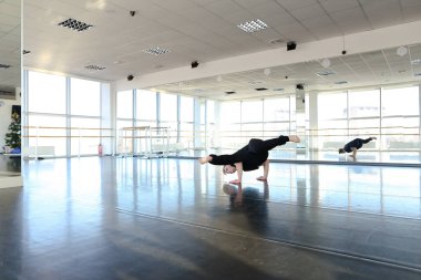 Sicim üzerinde oturan ve germe yapıyor genç dansçı.