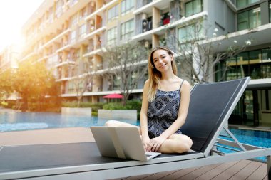 genç kadın kamera dizüstü pc ile açık havada uzaktan yakın Yüzme Havuzu ve apartmanı freelance arıyor