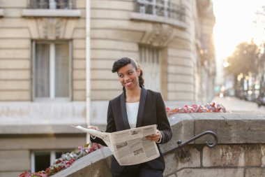 Melez gazeteci yüksek binası yakınındaki gazete okuma.