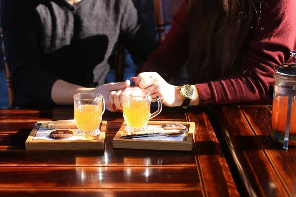 Couple sitting near table with sea-buckthorn broth in cafe discu