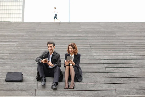 Чоловіки і жінки офісні працівники проводять перерву, сидячи на сходах — стокове фото