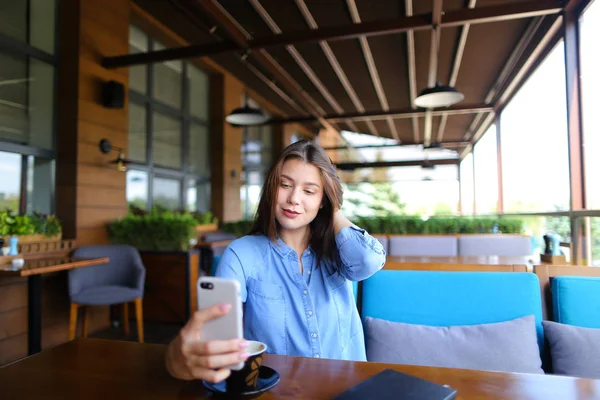 Encantadora chica haciendo selfie por teléfono inteligente con taza de café   . — Foto de Stock