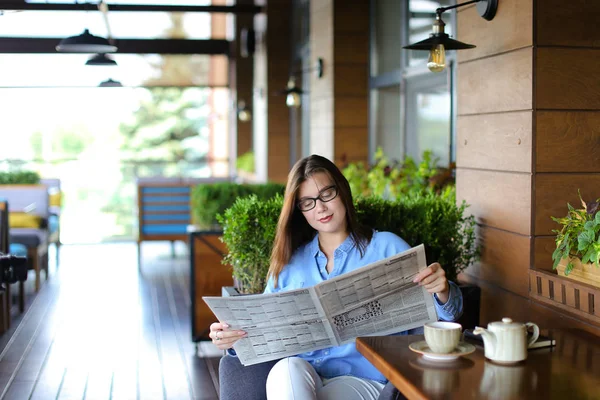 Encantadora mujer leyendo el periódico en el restaurante y tomando té — Foto de Stock
