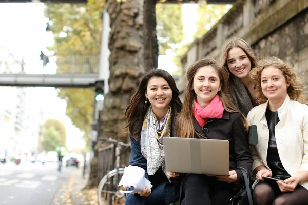 Étudiantes assises sur le banc et apprenant avec ordinateur portable et papa — Photo