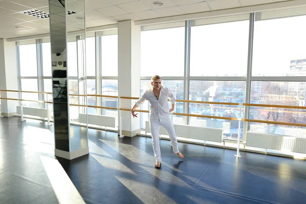 Young blonde dancer enjoys winning in white suit and makes warm