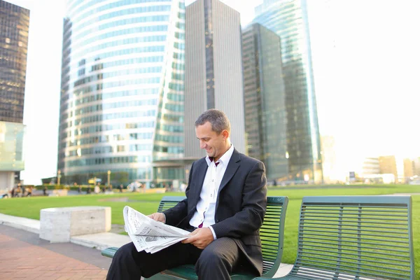 Empresário lendo jornal e olhando para o relógio lá fora ,  . — Fotografia de Stock