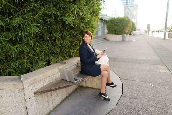 Affärskvinna att skriva meddelande och lyssnar på musik utanför med — Stockfoto