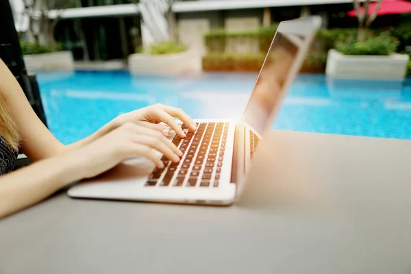 Cerrar los dedos de la mujer presionando el teclado en la piscina día soleado portátil — Foto de Stock