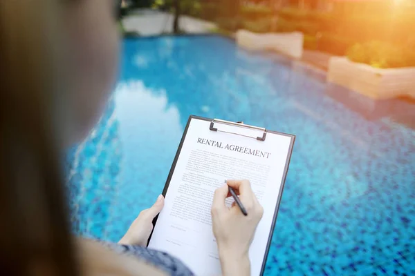 Primer plano retrato de la firma de contrato de alquiler en el fondo de la piscina. Frente utilizado con licencia Open Font — Foto de Stock