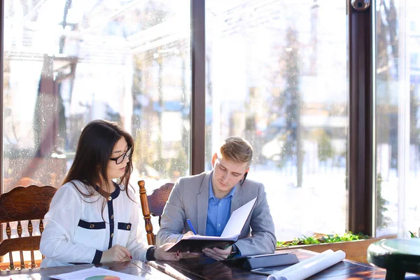 Female secretary talking with businessman at cafe and showing ca