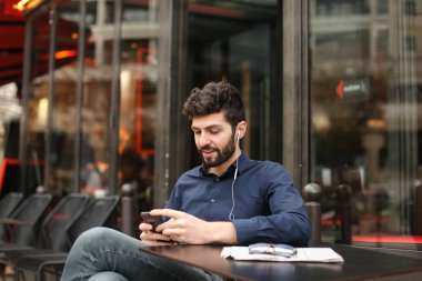 Öğrenci smartphone ve kafede kulaklık ile müzik dinlemek