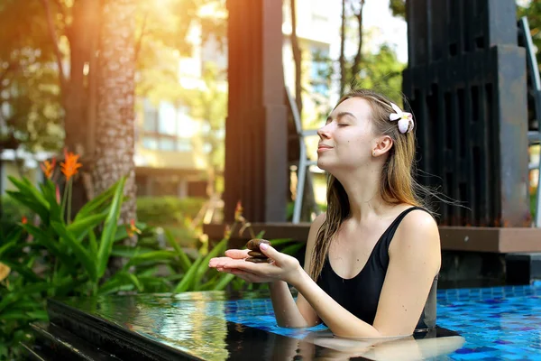 Mooie vrouw houdt van de cairn groep stenen, evenwicht in zwembad zonlicht — Stockfoto