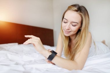 güzel kadın beyaz yatakta döşeme smartwatch bakarak