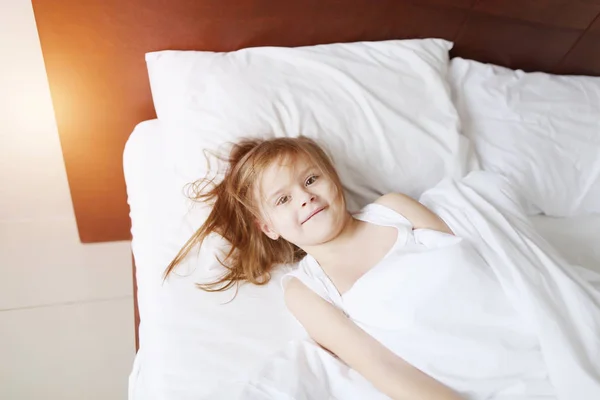 Портрет маленькой дочери глупая игра и улыбка в постели дома на солнечное утро — стоковое фото