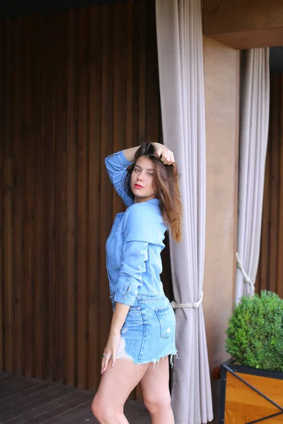 Chica bonita jugando con el pelo y mirando a la cámara cerca de la cafetería . — Foto de Stock