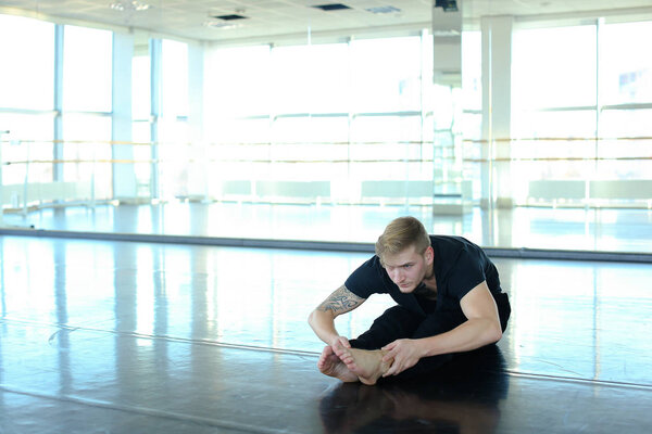 Dancer making leg stretching at gym.