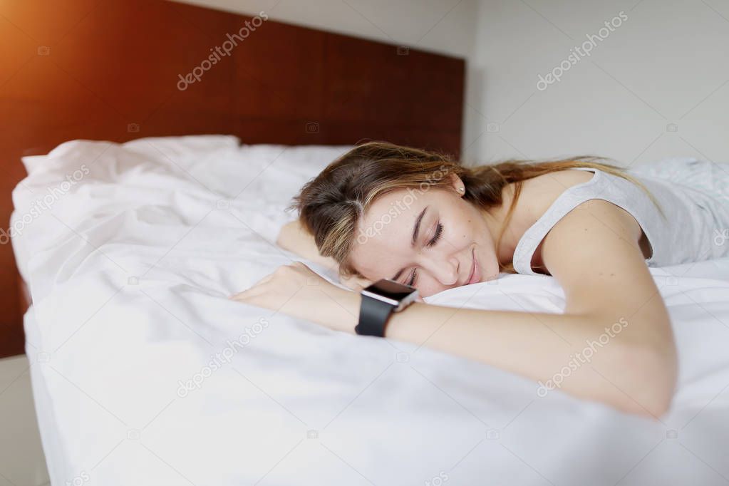 pretty young woman sleeping uses Smartwatch with accurate sleep tracking