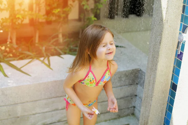 Chica divertida cerrar los ojos, gotas de agua caen sobre el niño en la ducha del traje de baño en el día soleado afuera — Foto de Stock