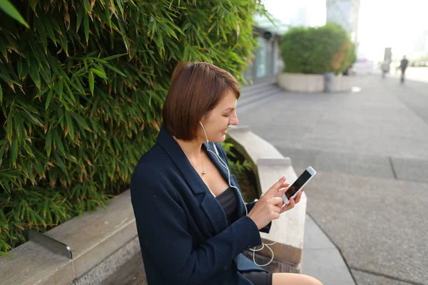 Secretaria escuchando música con auriculares y smartphone o — Foto de Stock