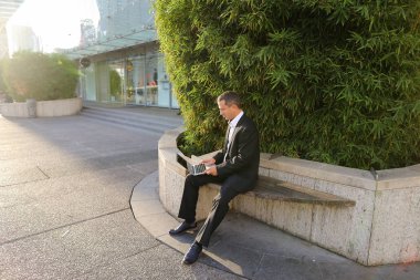 İşadamı çevre bitki dışarıda dizüstü bilgisayar ile çalışma  .