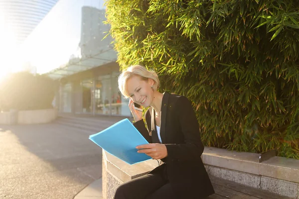 Secretaria hablando por teléfono inteligente con estuche de documentos al aire libre — Foto de Stock