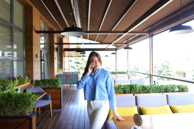 Kol sandalyede oturan ve smartphone vasıl tarafından konuşmak güzel kız