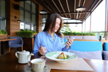 Kafede oturan, smartphone tarafından sohbet ve sahip güzel kadın 