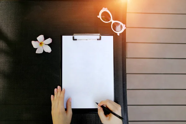 Närbild porträtt av kvinna händer håll tomma papper och penna på holiday solljus bakgrund med blomma och solsken. Framsidan som används med Open Font License — Stockfoto