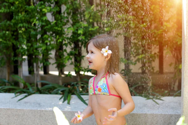 Retrato exterior de gotas de agua caen sobre la niña en la ducha del traje de baño en el día soleado — Foto de Stock