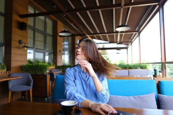 Młoda dziewczyna korzystających wietrznej pogody i grając z włosów w kawiarni — Zdjęcie stockowe