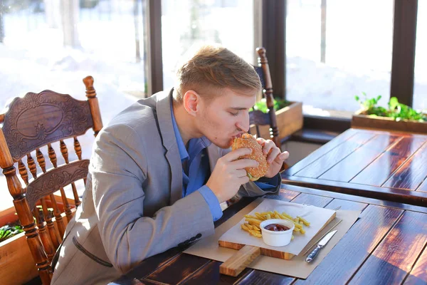 Geschäftsmann in grauer Jacke mit smarter Uhr beim Essen — Stockfoto