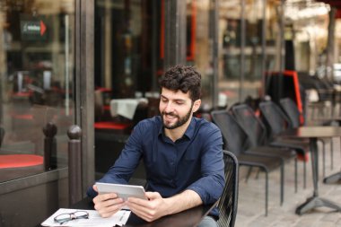 Hoşnutsuz adam online oyun tarafından tablet sokak café'de oynuyor..