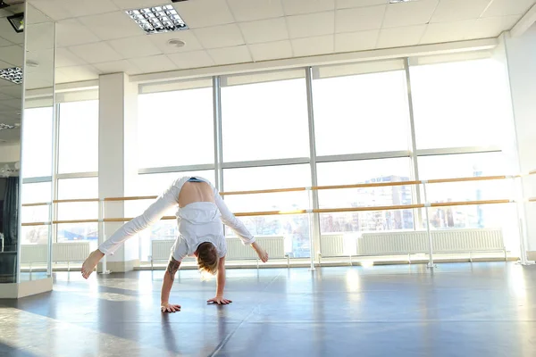 Blonde guy doing vigorous movements in white suit.